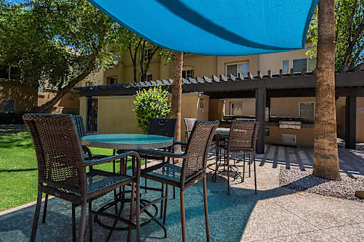 A patio with a table and chairs under a blue umbrella.at Palazzo Townhomes, Phoenix, 85008  
