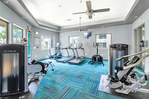 A gym with a variety of equipment including treadmills, stationary bikes, and weight machines.