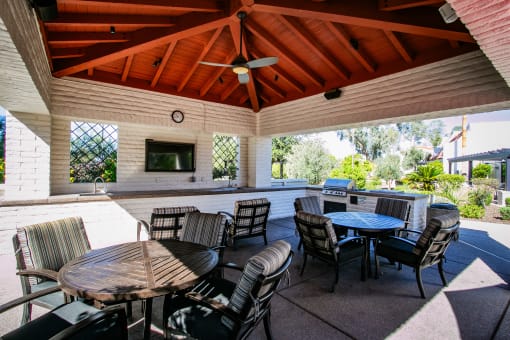 a covered patio with tables and chairs and a grill