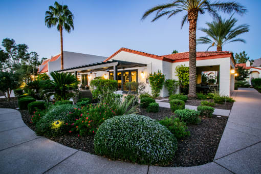 the front of a house with a garden and palm trees