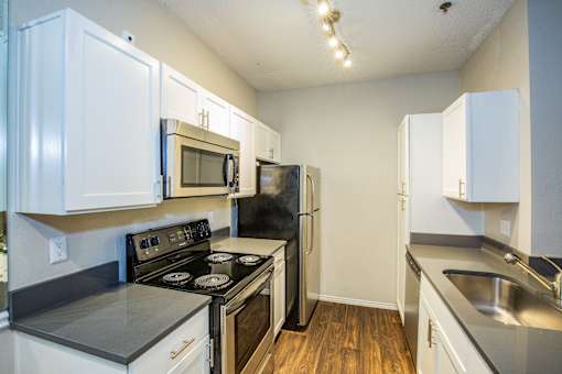 A kitchen with white cabinets and black appliances.