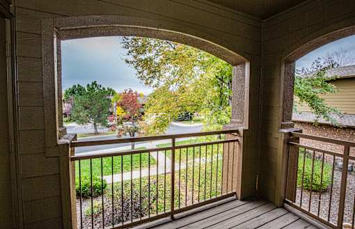 A view from a porch looking out to a street lined with trees.