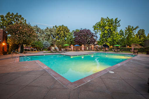 A swimming pool surrounded by trees and lounge chairs.