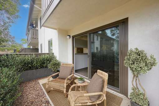 Apartments for Rent in Goleta, CA - Pacific Oaks - Private Patio Area with Two Chairs and Surrounding Wood Chips and Greenery.