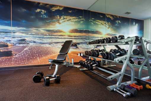 Goleta, CA, Apartments Near Target - Pacific Oaks - Fitness Center with Free Weights, Bench, and Mirror Wall.