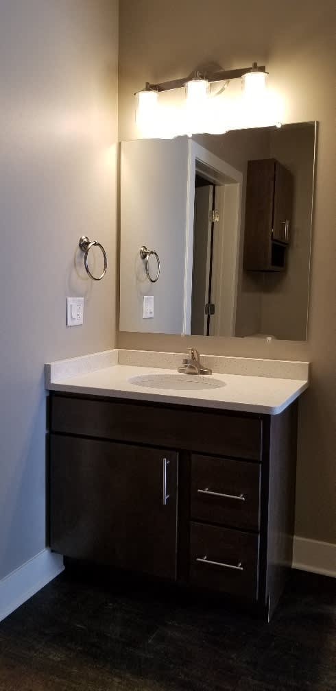 A bathroom vanity with a white countertop and a mirror above it.