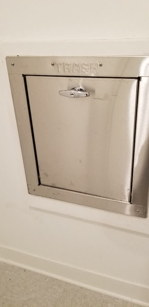 A metal trash can with a handle and a latch.
