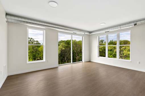 A room with wooden floors and large windows overlooking a green landscape.