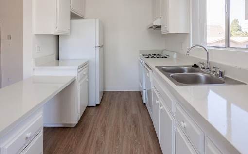 A white kitchen with a sink and a stove.