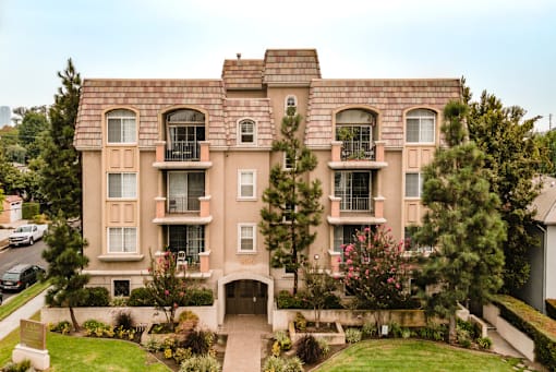 A large apartment building with a green lawn in front at Lido Apartments - 2810 S Sepulveda, Los Angeles CA 90064