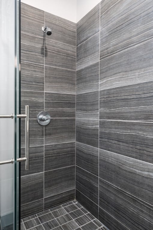 a tiled bathroom with a shower and a glass door at Lido Apartments - 4025 Grandview, California, 90066