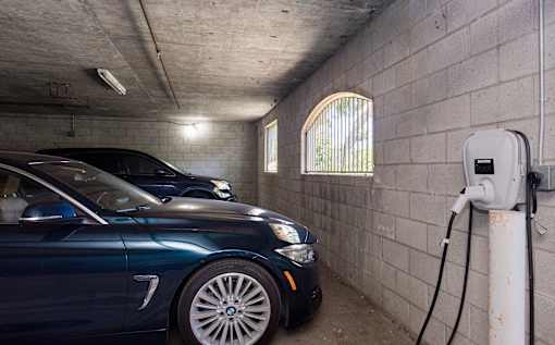 A blue car is parked in a parking garage and charging its battery.