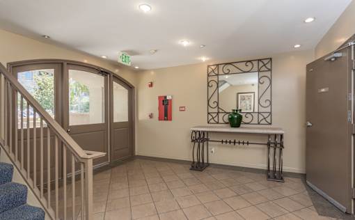 A hallway with a bench, a fire extinguisher, and a mirror.