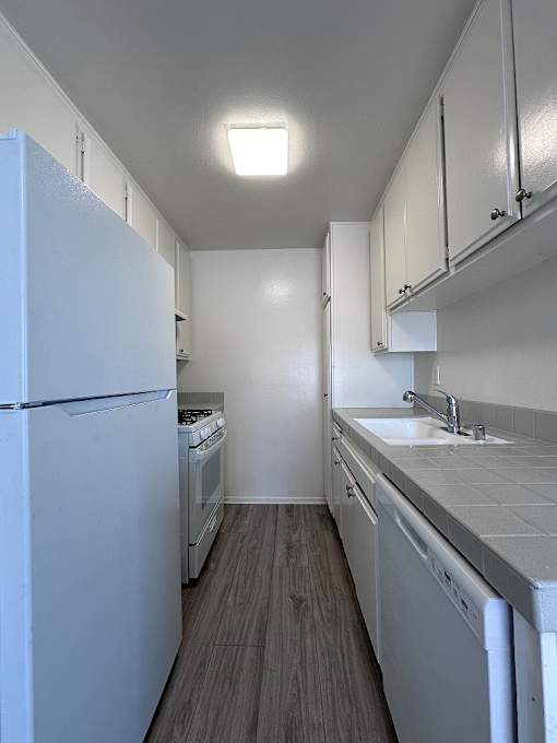 A kitchen with white appliances and cabinets.