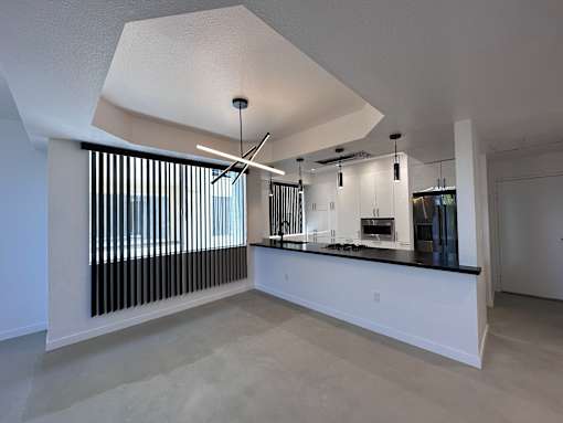 A modern kitchen with a large island and a window with vertical blinds.