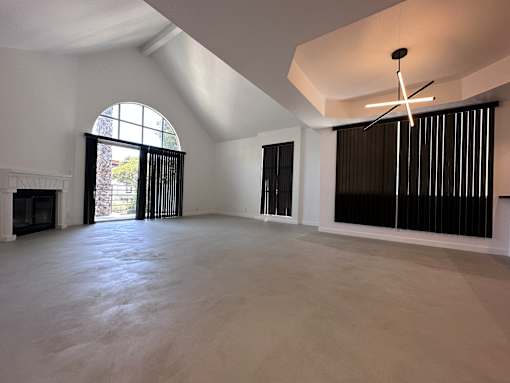 A large, empty room with a fireplace and a large window.