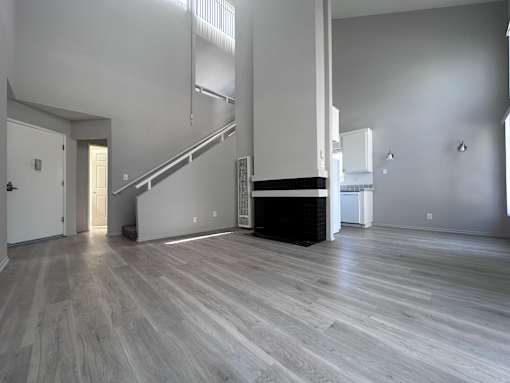 A spacious room with a staircase and a fireplace.