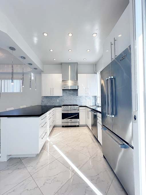 A modern kitchen with a stainless steel refrigerator and white cabinets.