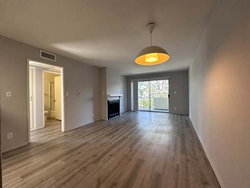 A room with wooden floors and a hanging light fixture at Lido Apartments - 3130 Bagley Ave, Los Angeles, 90034