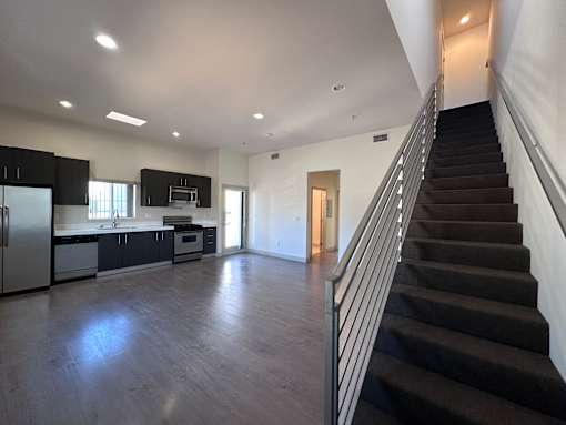 Open kitchen with staircase and dark flooring at Lido - 3630 Mentone Ave Apartments, Los Angeles, CA