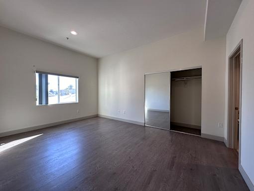 Empty bedroom with mirrored closet and dark flooring at Lido - 3630 Mentone Ave Apartments, Los Angeles, 90034