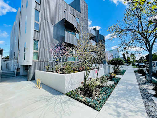 A modern building with a grey facade and a white planter box in front of it.