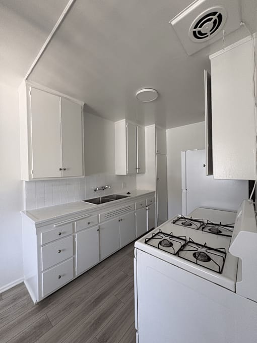 A white kitchen with a stove and cabinets.