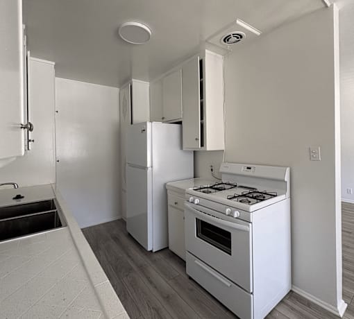 A white kitchen with a stove and refrigerator.