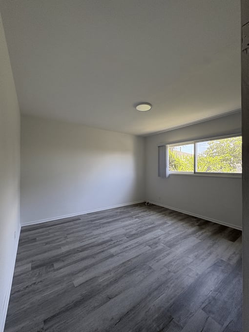 A room with a window and grey flooring.