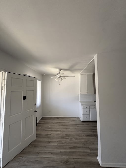 A white door is open to a room with a ceiling fan.