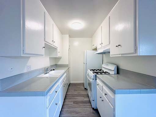 A kitchen with white cabinets and a stove top oven.