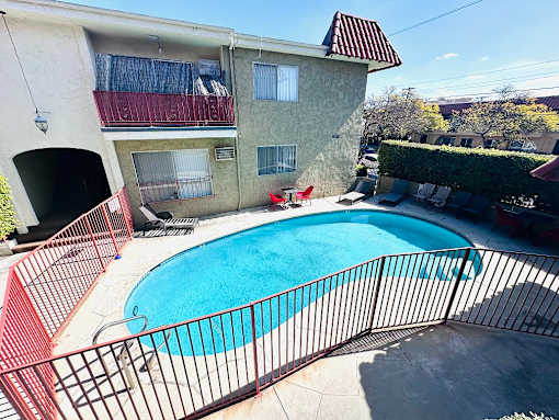 A small pool in a fenced in area outside a building.