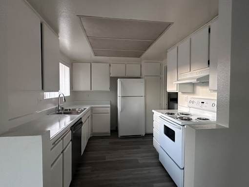 A white kitchen with a refrigerator, oven, and sink.at Lido Apartments - 101-197 N Ridgeway, Anaheim California