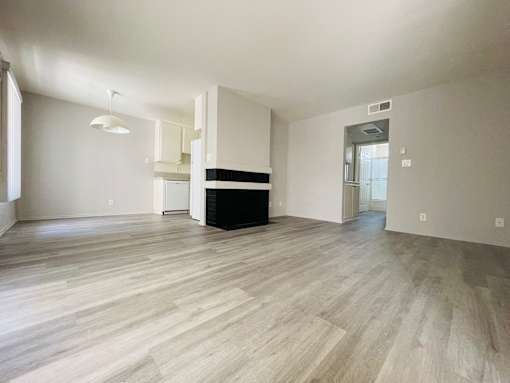 A spacious room with light wood flooring and white walls.