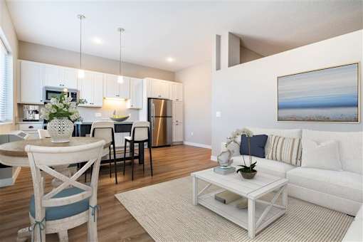 A modern living room with a dining area and kitchen in the background.