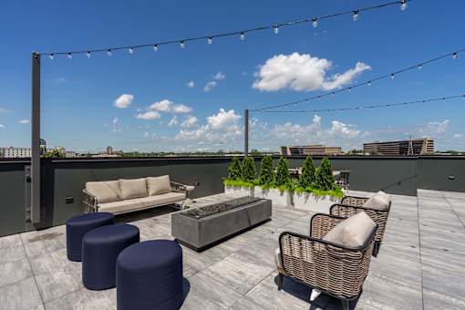 A rooftop patio with furniture and string lights.