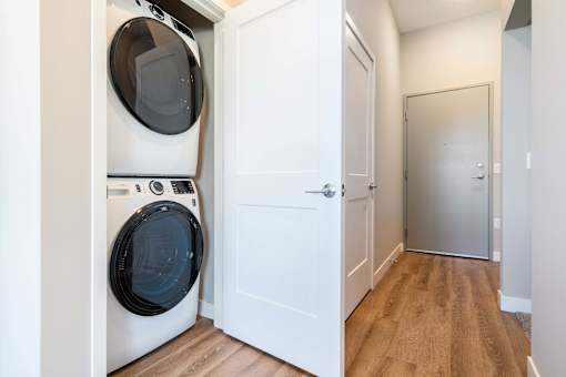 A white door is open to a hallway with a washer and dryer in the other room.