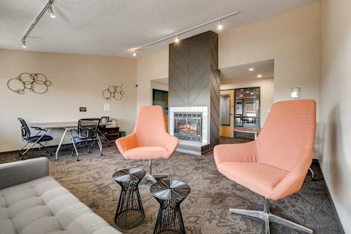 A living room with a fireplace and two orange chairs.