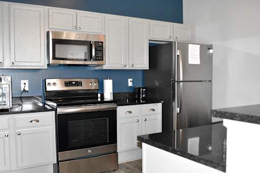 A kitchen with white cabinets and a black counter.