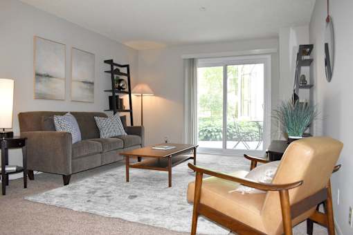 A living room with a brown couch, a wooden coffee table, and a tan leather chair.