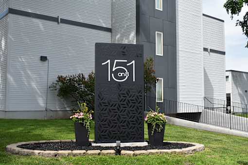 Monument sign at the entrance of  151 on 8 surrounded by landscaping.