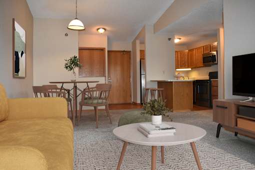 A living room with a yellow couch and a white coffee table.