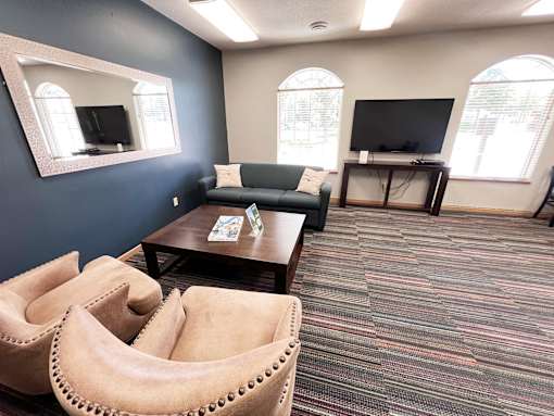 A living room with a couch, chairs, and a television.
