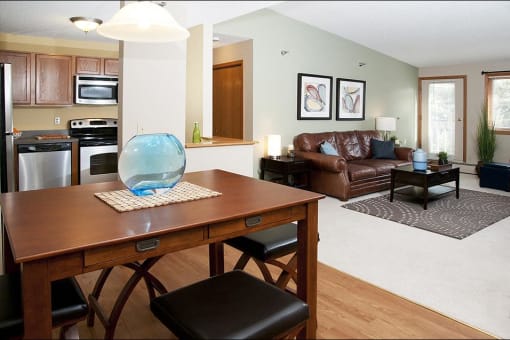 Dining room and living room areas with a large leather couch and a rectangular brown table