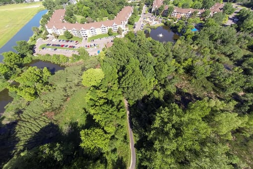 High altitutde view of property, showing buildings, trees, and a bike trail