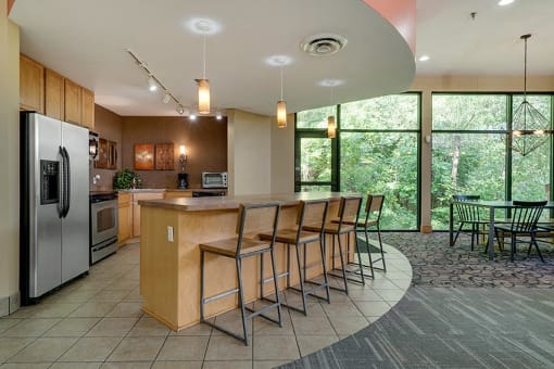 Community room with bar seating, a kitchen, and large windows