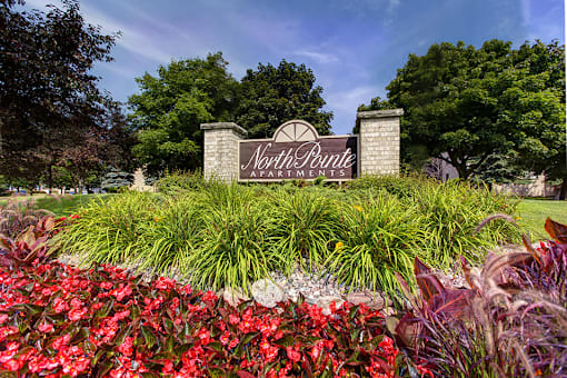 A sign for North Point Apartments is surrounded by flowers and greenery.