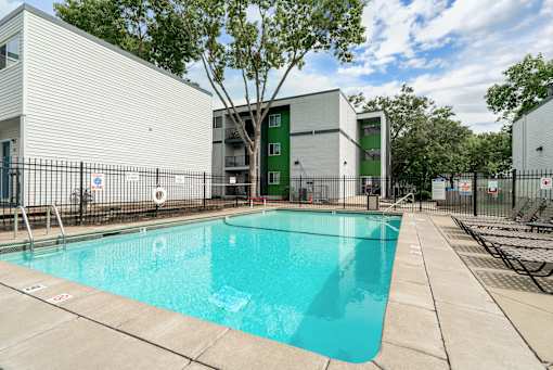 A swimming pool in front of a building with a green door.