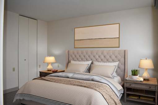 A bedroom with a large bed and two lamps on side tables.
