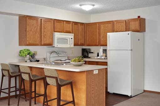 A kitchen with a white refrigerator and wooden cabinets.